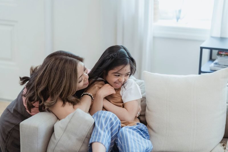 Mother and daughter laughing together on a sofa at home