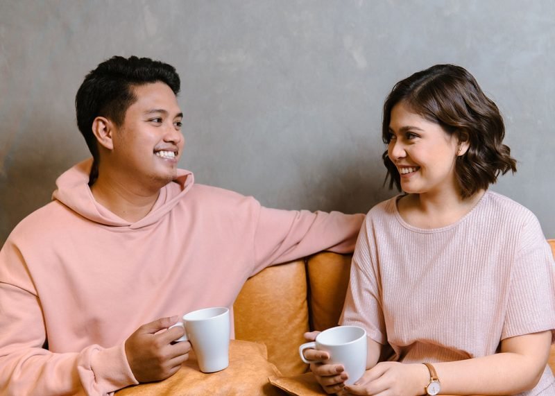 Smiling couple chatting over coffee on a cosy sofa