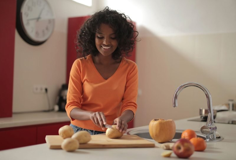 Smiling woman preparing vegetables in a bright kitchen
