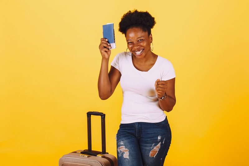 Happy woman holding a passport next to a suitcase